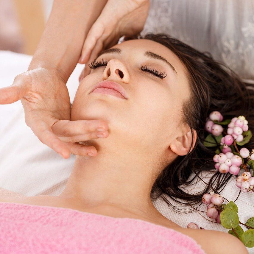 a woman lying on a massage table with a hand on her chin and looking relaxed